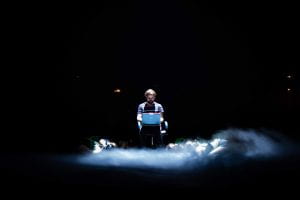 Man seated using laptop under stark light in smoke